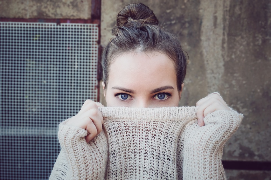 a woman covering her face with a sweater